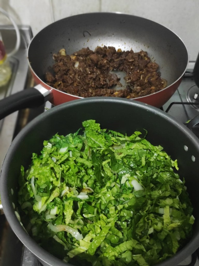 A foto mostra duas panelas, uma com couve refogada e a outra com carne moída frita.
